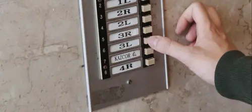 A hand pressing a doorbell on a front door, illustrating younger generations preferring to text or call instead.